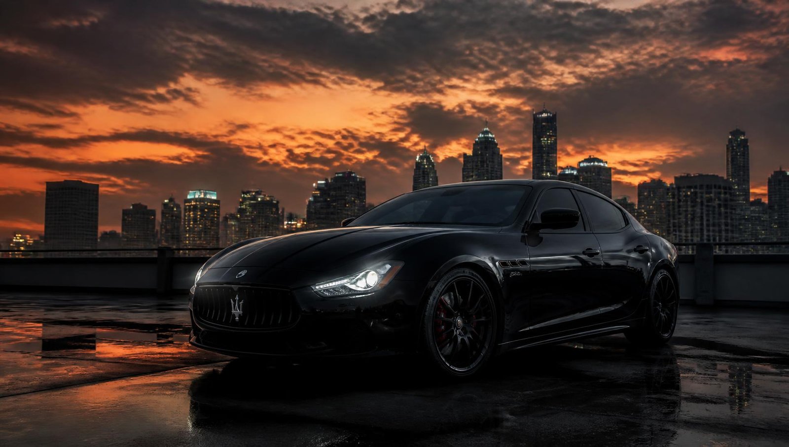 Black luxury sports sedan at sunset in an urban skyline setting